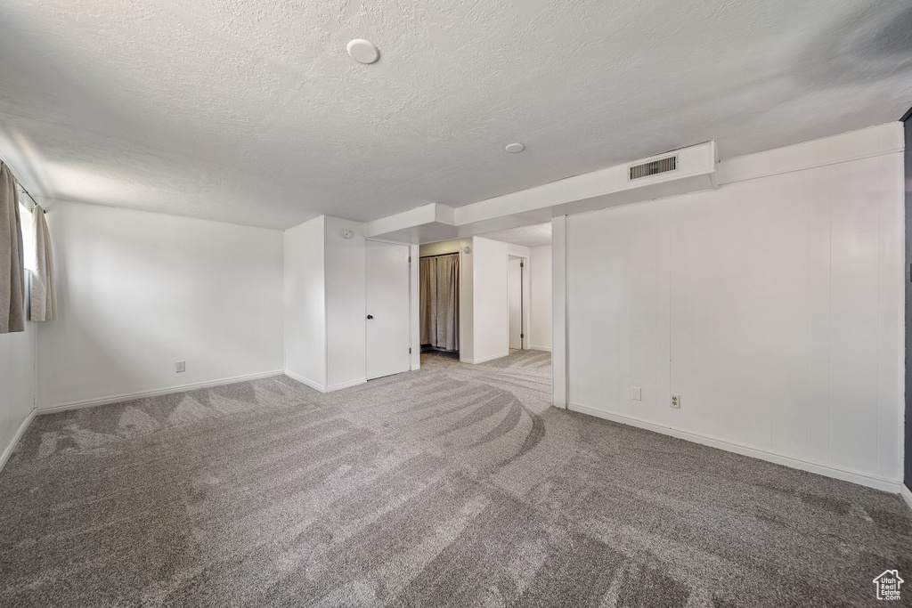 Empty room with a textured ceiling and light colored carpet