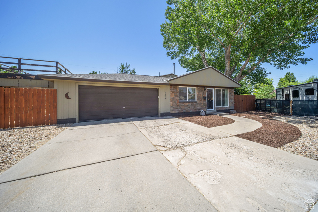 View of front of home featuring an attached garage, driveway, and stone siding