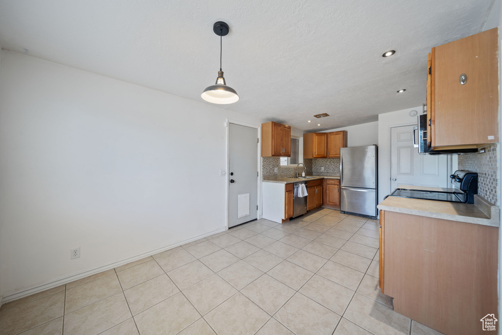 Kitchen featuring appliances with stainless steel finishes, tasteful backsplash, light countertops, brown cabinets, and recessed lighting