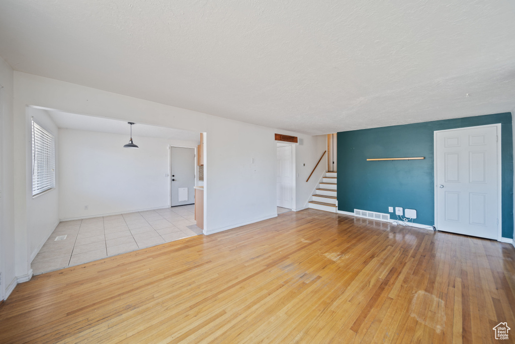 Spare room featuring stairway, wood-type flooring, and a textured ceiling
