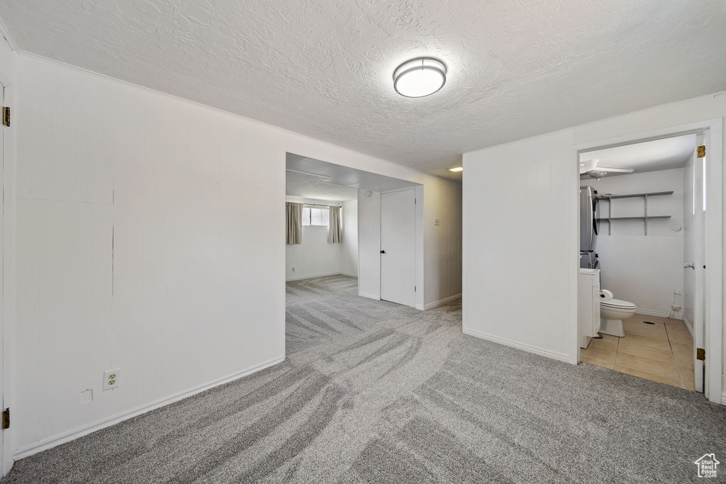 Carpeted empty room featuring a textured ceiling and baseboards