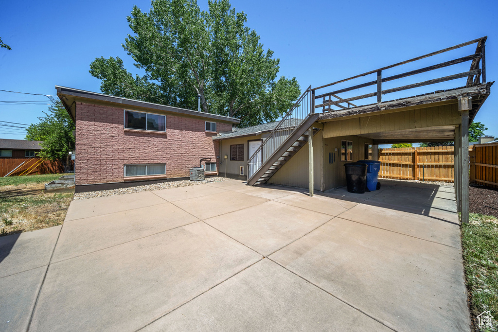 View of front of house featuring driveway, a carport, and stairway