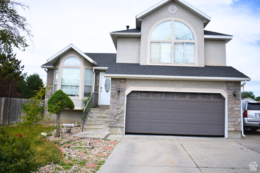View of front of property with stone siding, driveway, stucco siding, and an attached garage