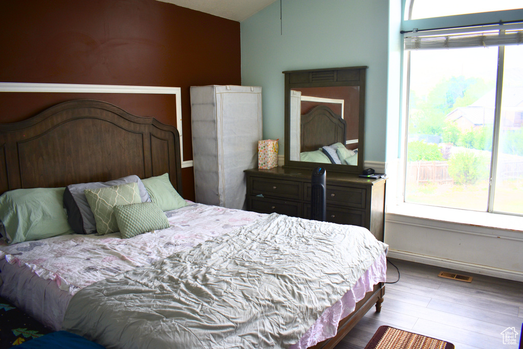 Bedroom featuring multiple windows, lofted ceiling, and wood finished floors