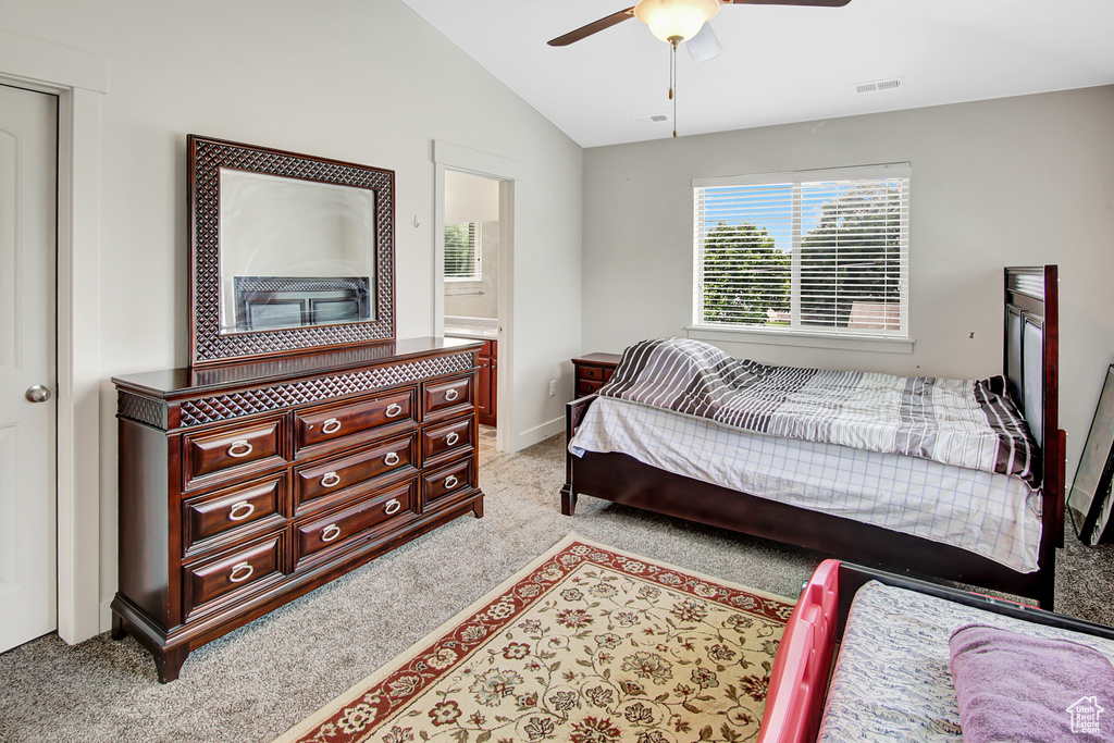 Bedroom with light colored carpet, vaulted ceiling, a ceiling fan, and connected bathroom