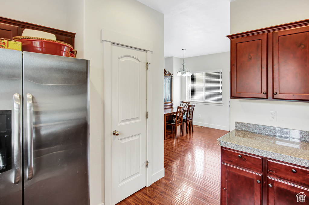 Kitchen with stainless steel refrigerator with ice dispenser, reddish brown cabinets, dark wood finished floors, and a chandelier