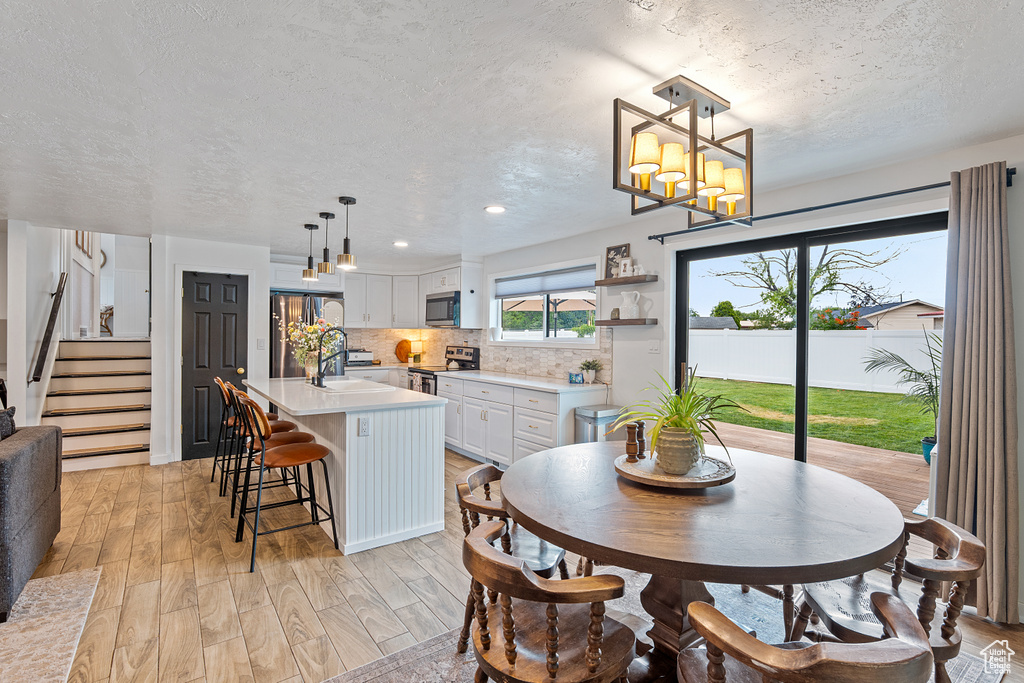 Dining space featuring a textured ceiling, light wood finished floors, recessed lighting, stairway, and a chandelier