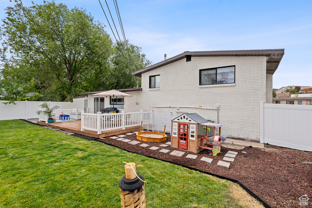 Rear view of property with a wooden deck, brick siding, and a fenced backyard