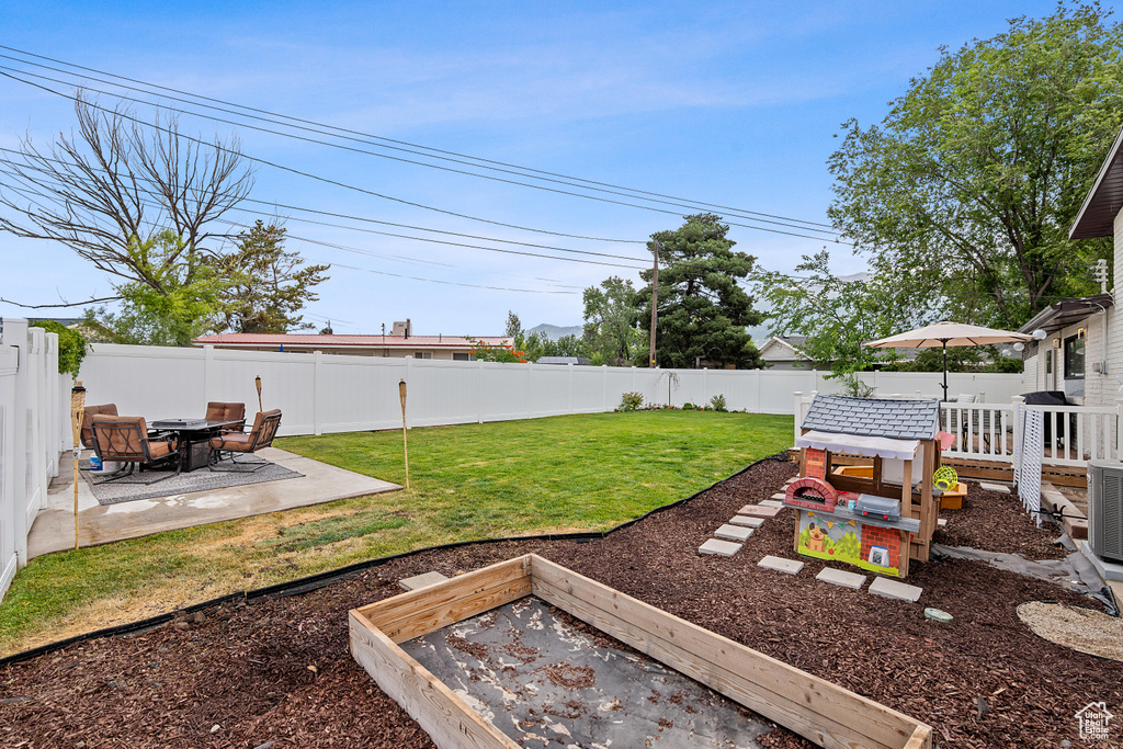 Fenced backyard featuring a patio and a vegetable garden