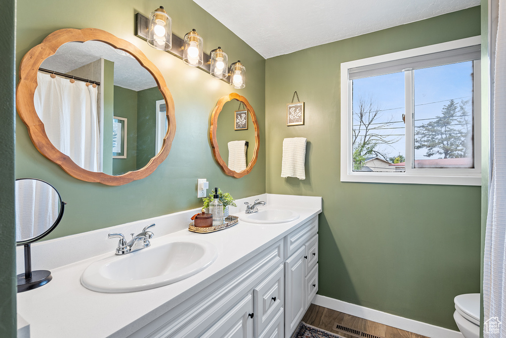 Bathroom featuring double vanity, wood finished floors, and curtained shower