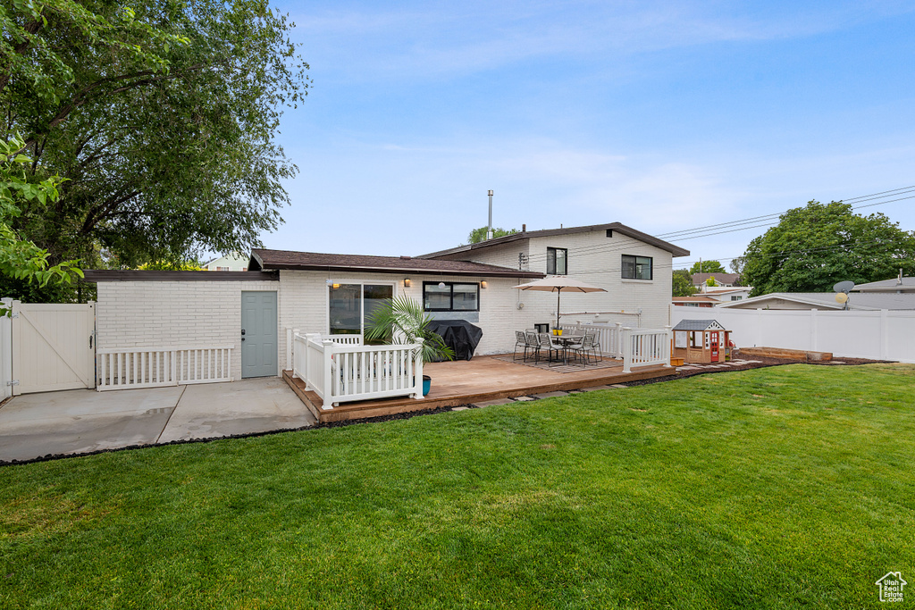 Back of house featuring a fenced backyard, a deck, a gate, and brick siding