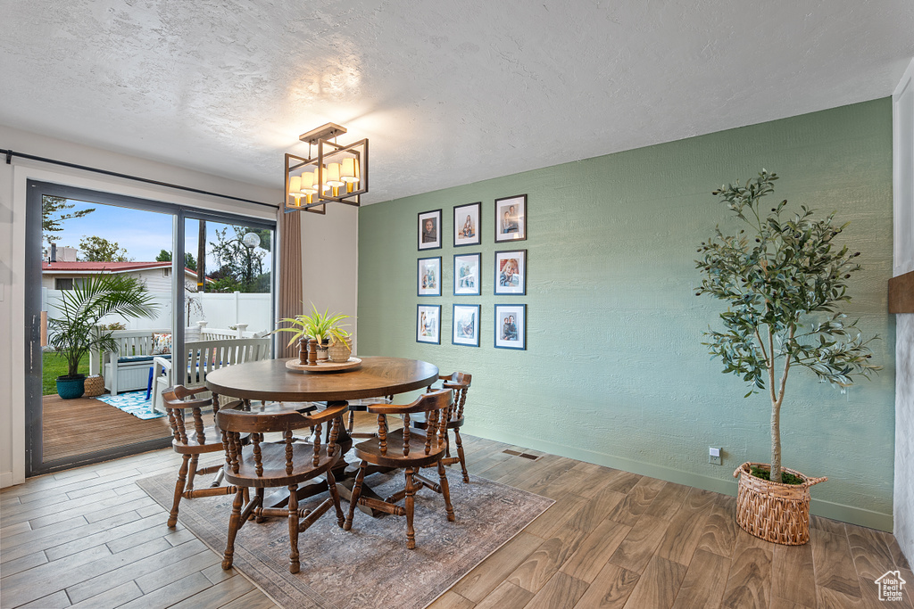 Dining space featuring light wood-type flooring, a chandelier, and a textured ceiling