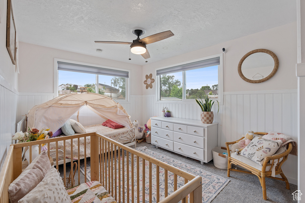 Carpeted bedroom featuring wainscoting, a textured ceiling, and a ceiling fan