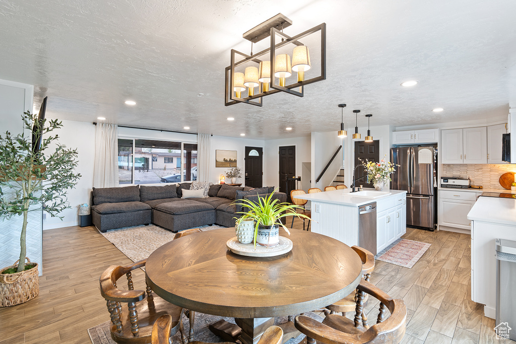 Dining room featuring stairway, light wood-type flooring, recessed lighting, and a chandelier