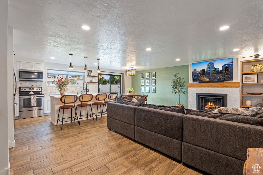 Living room featuring a fireplace, light wood-style flooring, and recessed lighting