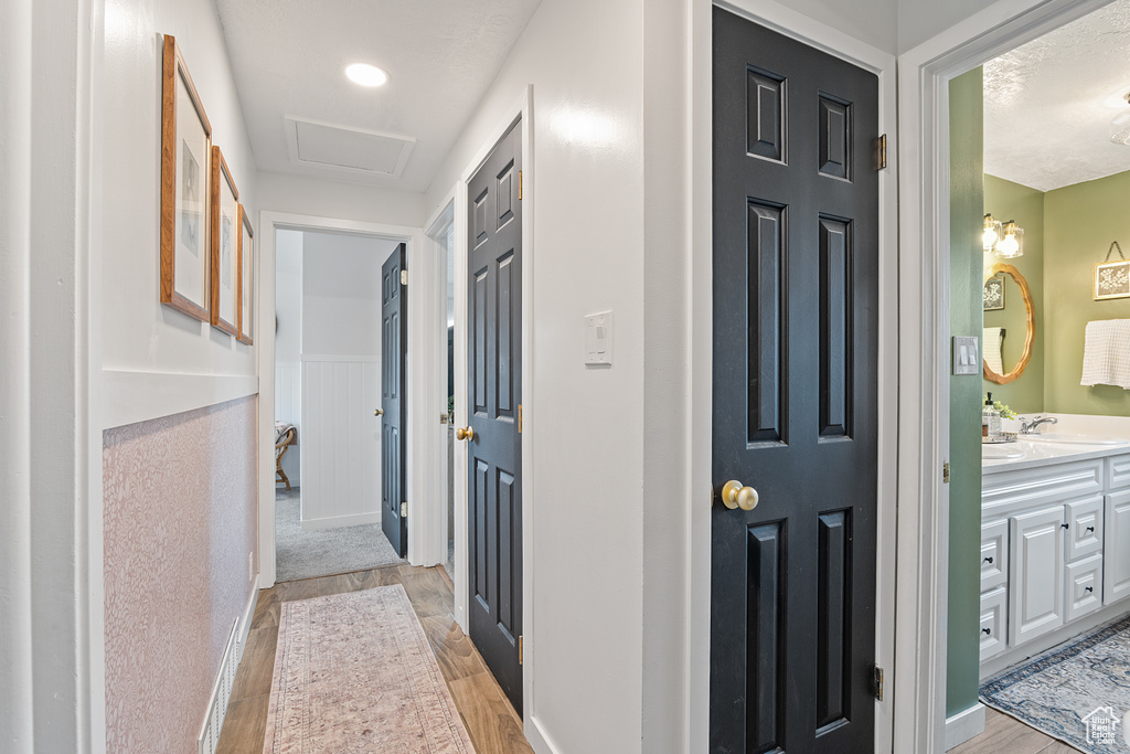Corridor with light wood-type flooring and attic access