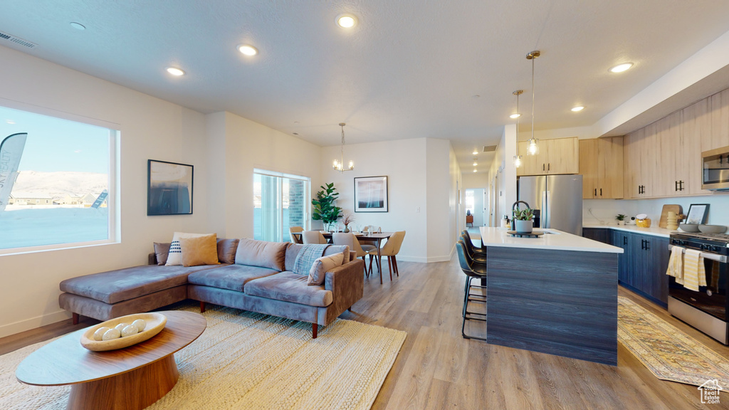 Living room featuring light wood-style flooring, a chandelier, and recessed lighting