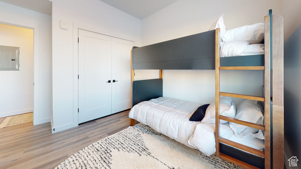 Bedroom featuring electric panel, wood finished floors, and a closet