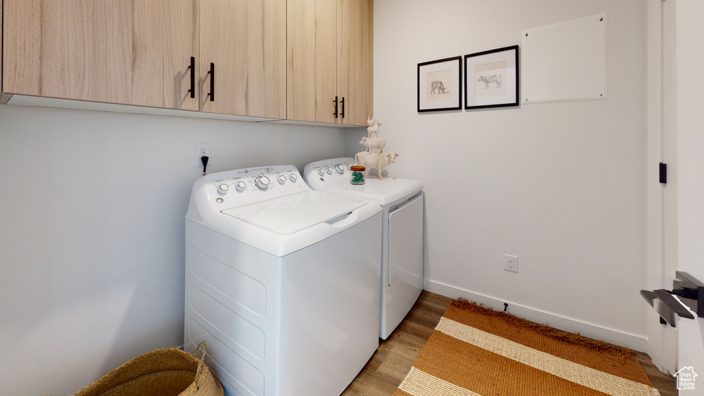 Laundry room with cabinet space, separate washer and dryer, and light wood-type flooring