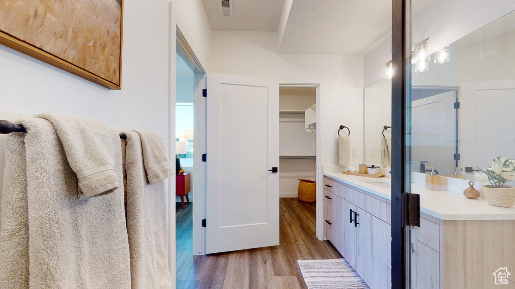 Full bath with wood finished floors, vanity, and a walk in closet