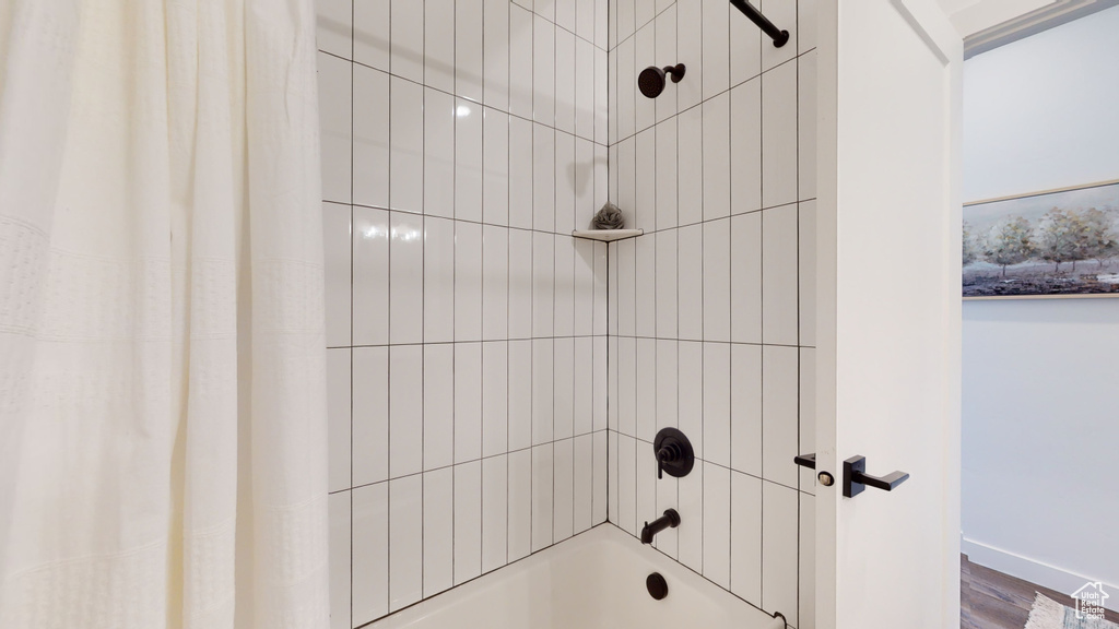 Bathroom featuring shower / bath combo and wood finished floors
