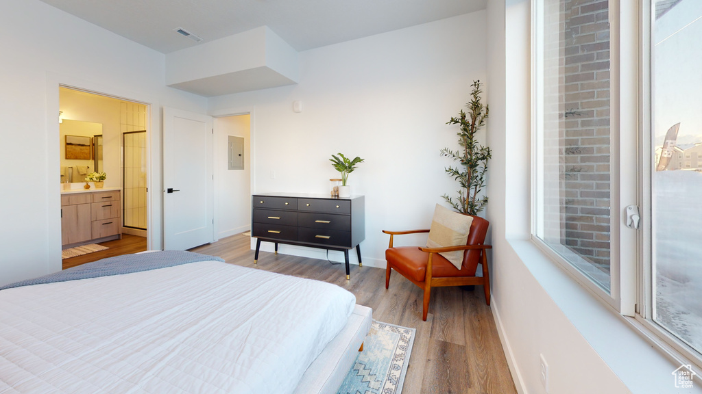 Bedroom with light wood-style flooring, electric panel, and multiple windows