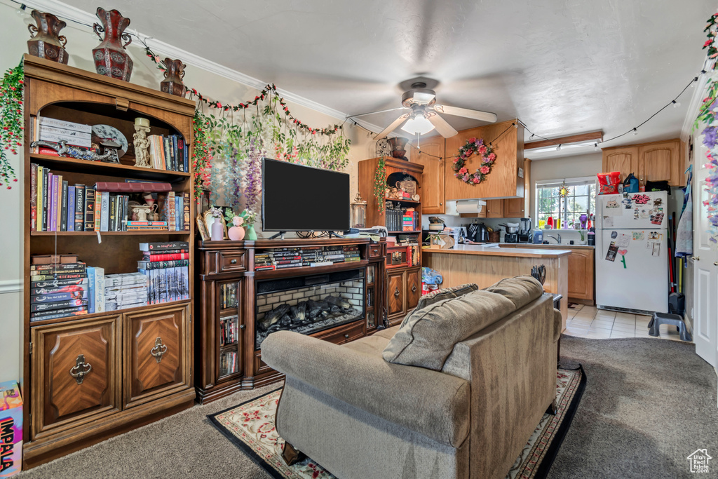Living area featuring ceiling fan, light colored carpet, crown molding, and light tile patterned flooring