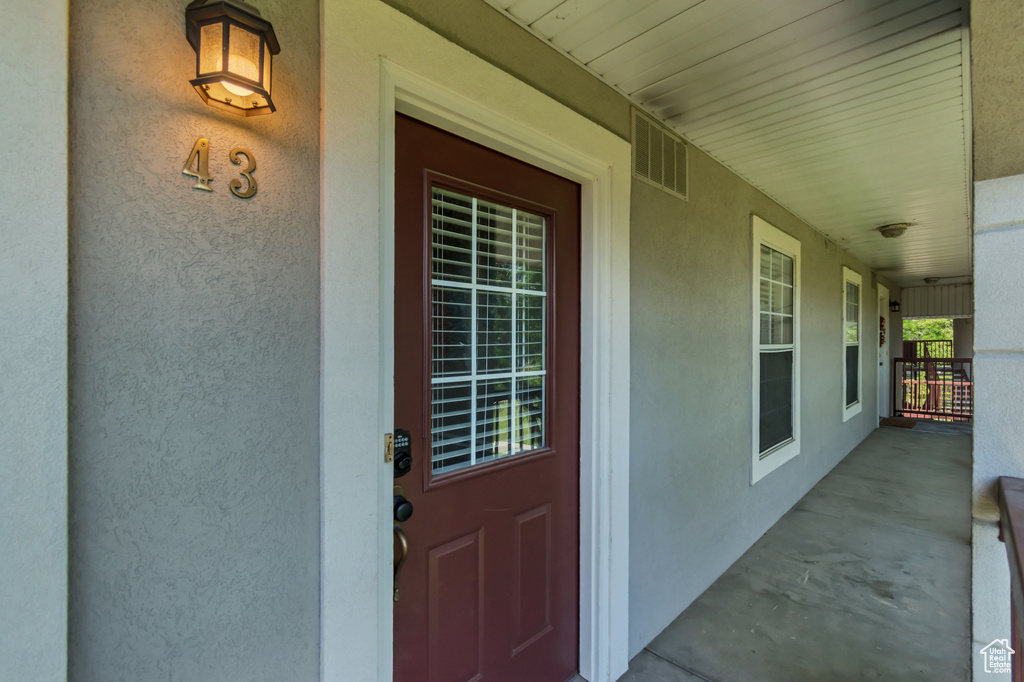 Doorway to property featuring stucco siding and a porch