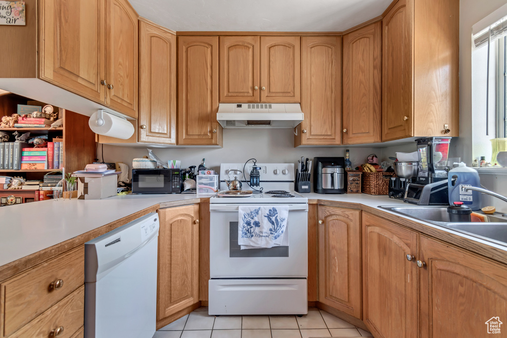 Kitchen featuring white appliances, under cabinet range hood, light countertops, and light tile patterned floors
