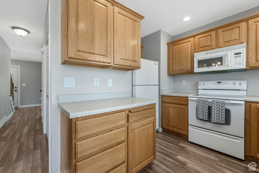 Kitchen with white appliances, dark wood-style floors, and light countertops