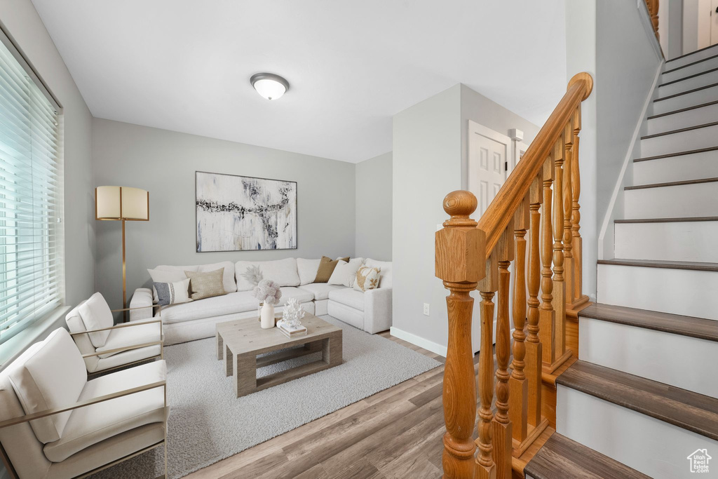 Living area with wood finished floors, healthy amount of natural light, and stairway