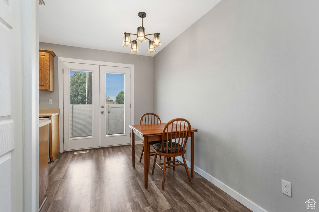 Dining room with french doors, dark wood-style floors, and a chandelier