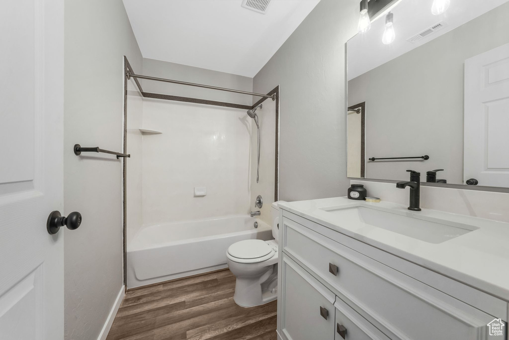 Bathroom with vanity, wood finished floors, and bathing tub / shower combination
