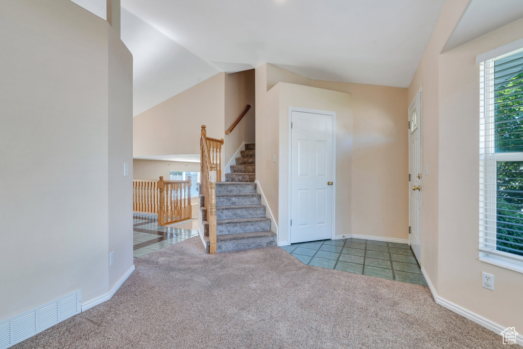 Carpeted foyer entrance featuring lofted ceiling, stairway, and tile patterned floors