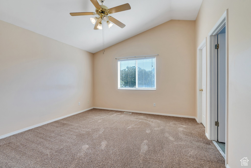 Unfurnished bedroom featuring carpet, vaulted ceiling, and a ceiling fan