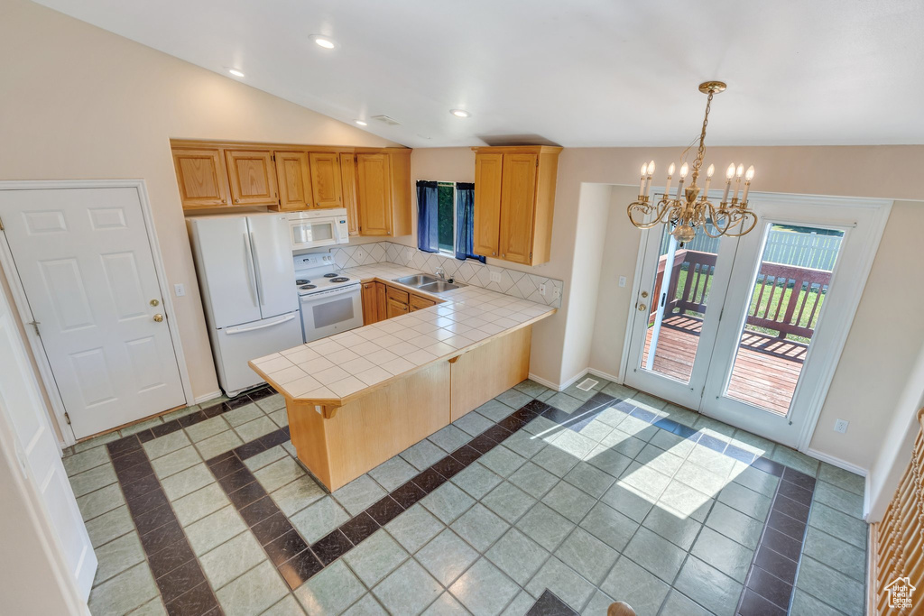 Kitchen with white appliances, inlaid floor details, a chandelier, a peninsula, and tile counters