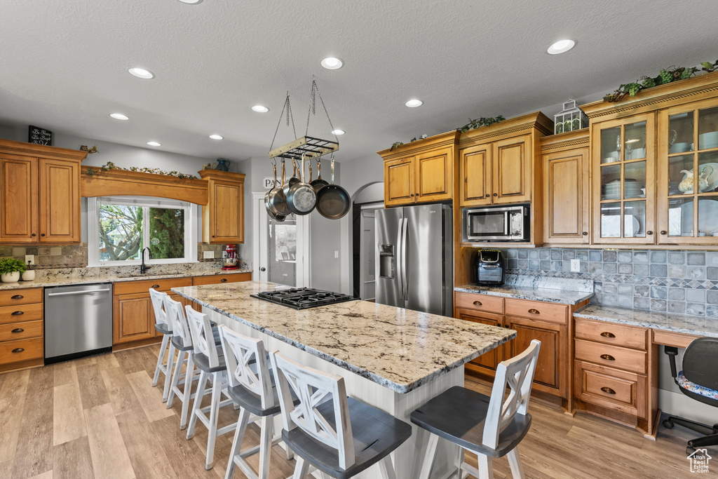 Kitchen with stainless steel appliances, a breakfast bar, a center island, tasteful backsplash, and recessed lighting