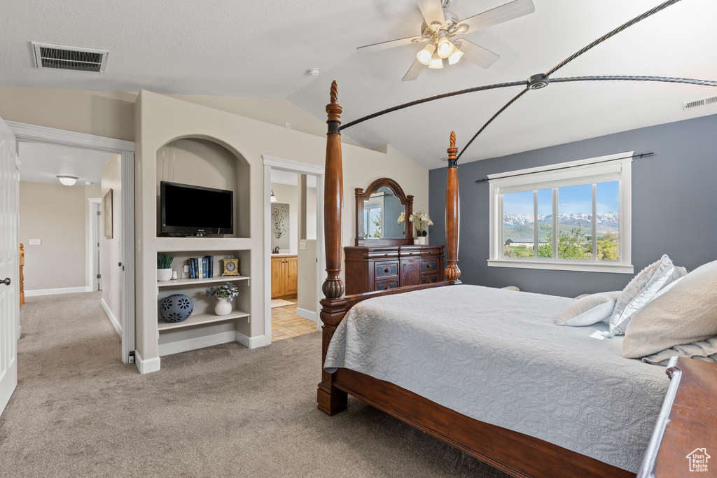 Carpeted bedroom with vaulted ceiling, connected bathroom, and ceiling fan