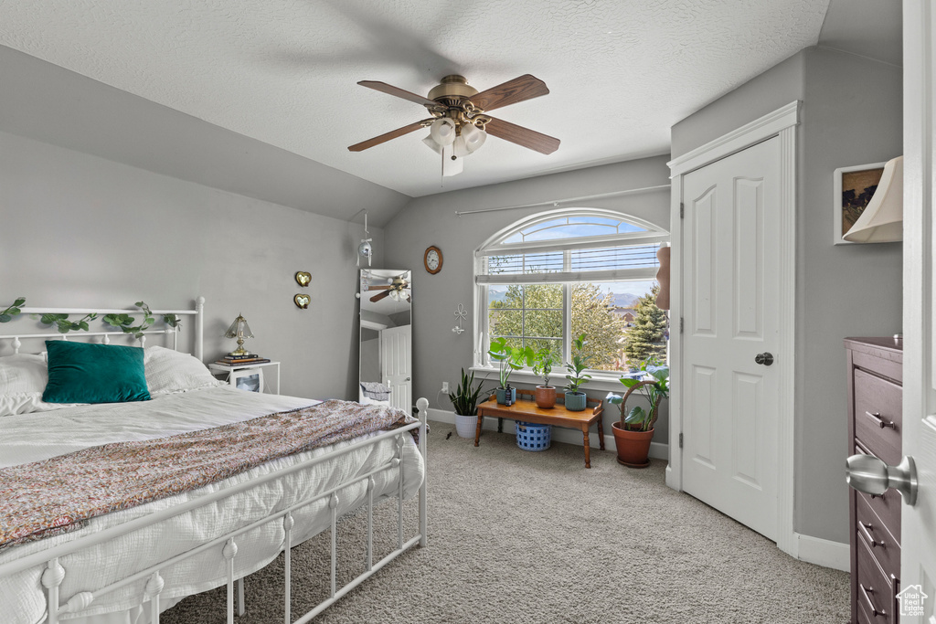 Bedroom with light colored carpet, vaulted ceiling, and a ceiling fan