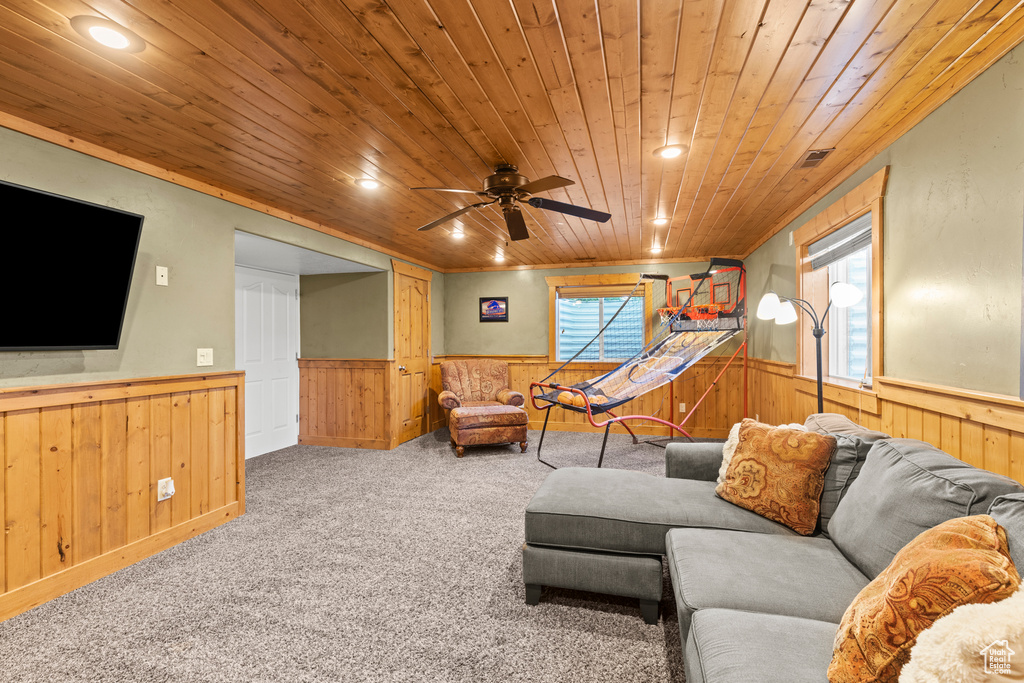 Carpeted living area with wainscoting, wood ceiling, wooden walls, ceiling fan, and recessed lighting
