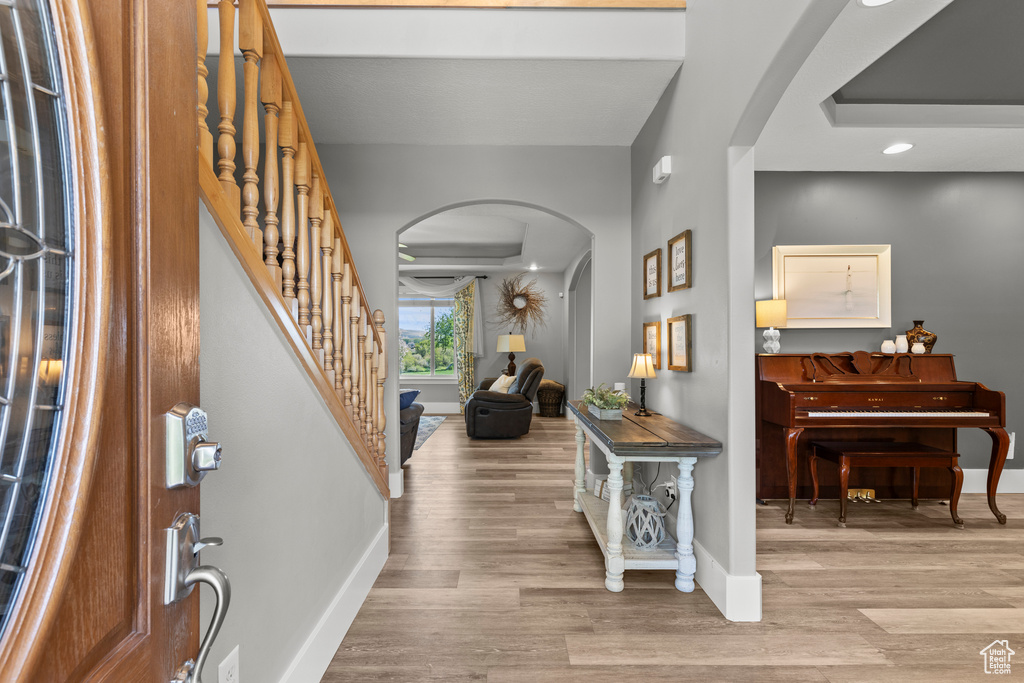 Entryway with arched walkways, wood finished floors, stairway, and recessed lighting