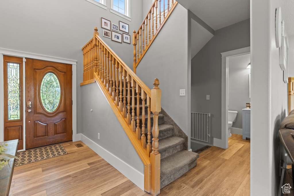 Foyer featuring wood finished floors, stairs, and a towering ceiling