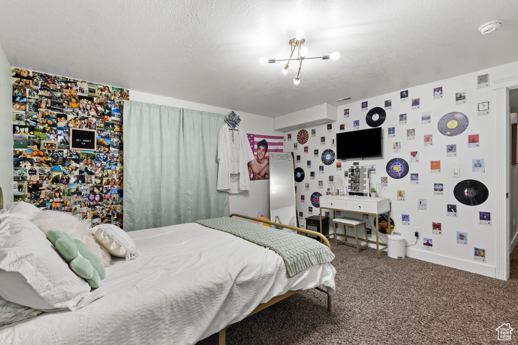 Bedroom featuring wallpapered walls, carpet flooring, a chandelier, and a textured ceiling