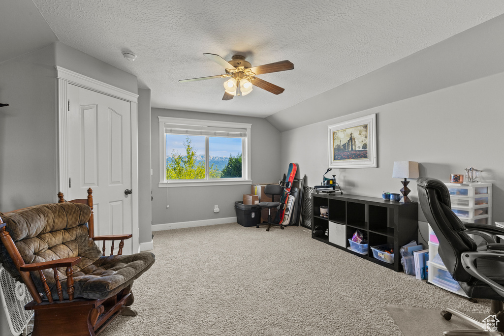 Carpeted office with ceiling fan, vaulted ceiling, and a textured ceiling