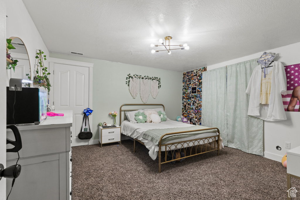 Carpeted bedroom with a chandelier and a textured ceiling