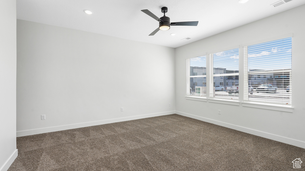 Empty room featuring dark colored carpet, recessed lighting, and a ceiling fan