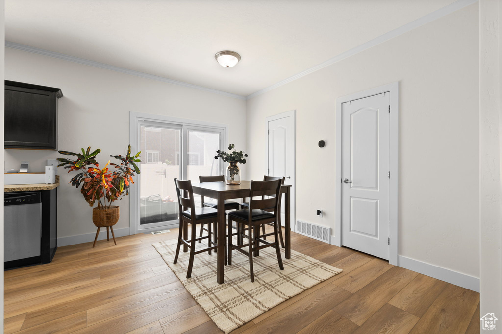Dining area with ornamental molding and light wood-style floors