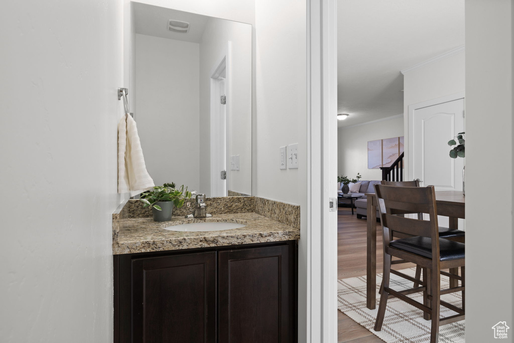 Bathroom with wood finished floors, vanity, and ornamental molding