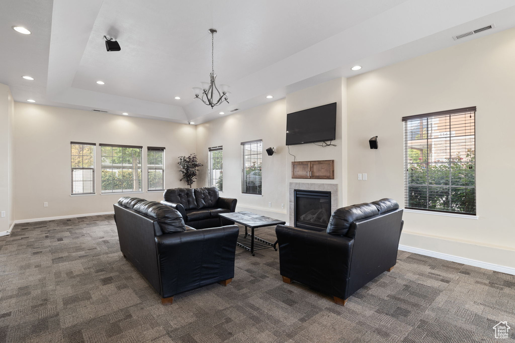 Living room with recessed lighting, dark colored carpet, a tile fireplace, and a chandelier