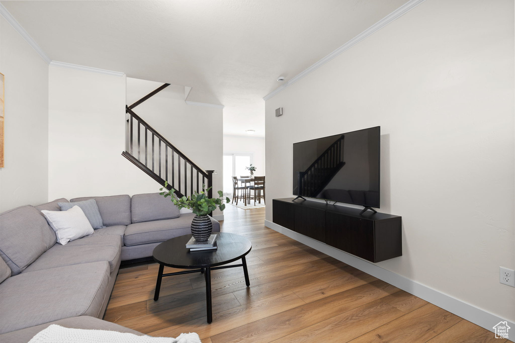 Living room with stairway, crown molding, and wood finished floors